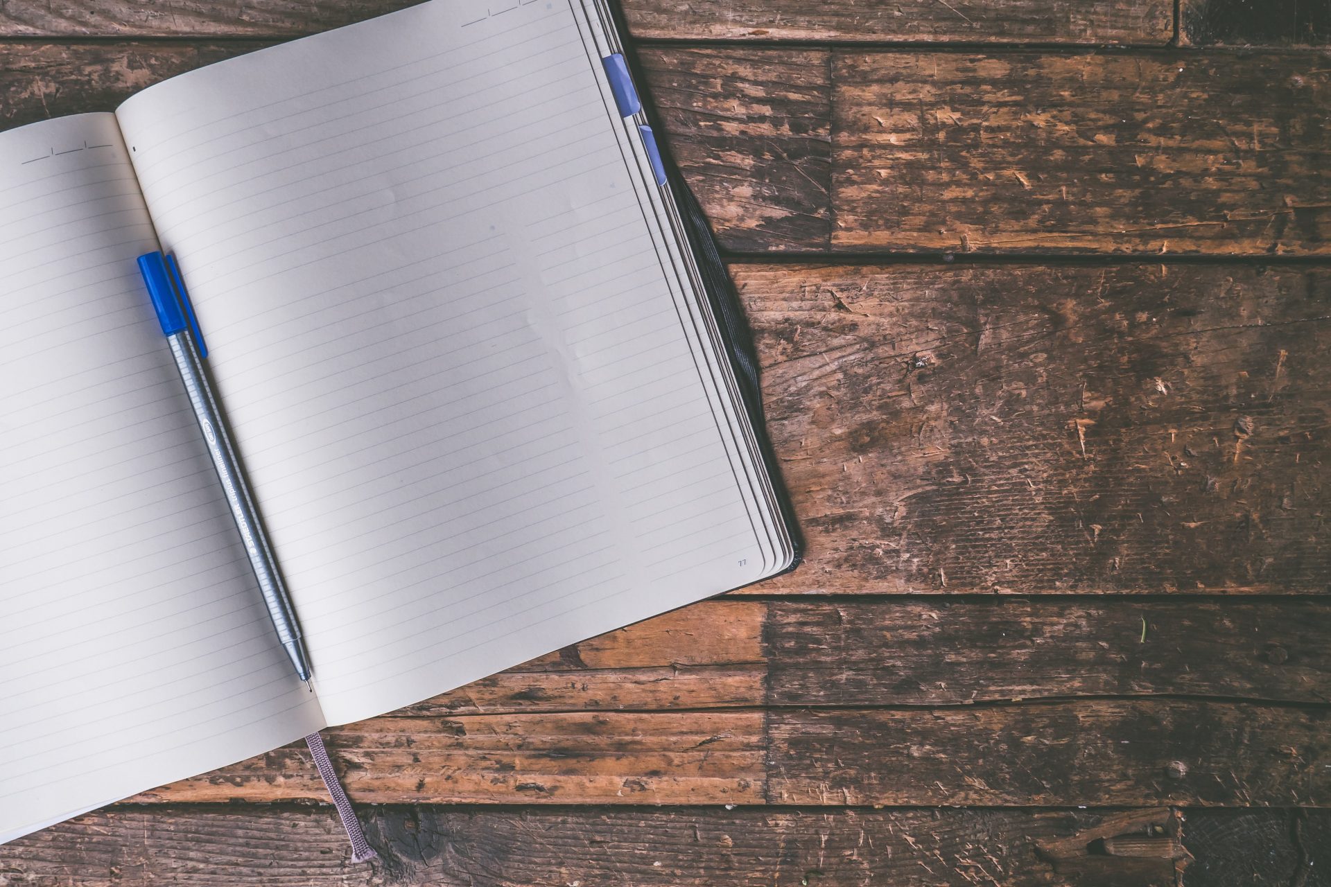 note book and pen on wooden table with content writing written in white across center