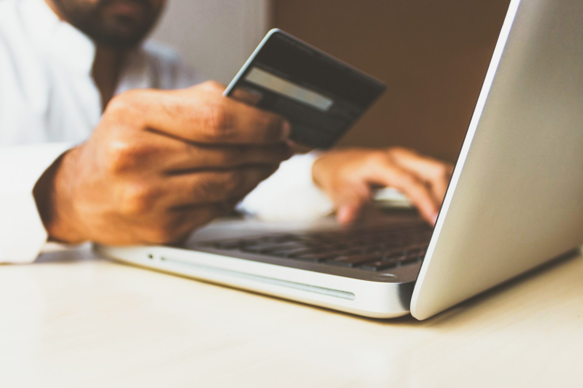 person making a purchase on their computer with their credit or debit card in hand with custom ecommerce written across the image